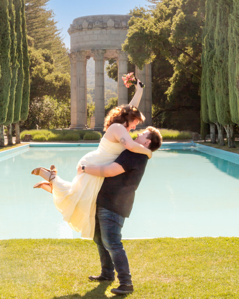 A trans man lifts his fiancée in the air during their engagement photoshoot