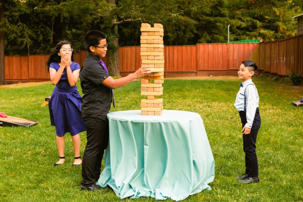 a huge jenga tower and kids playing with it 