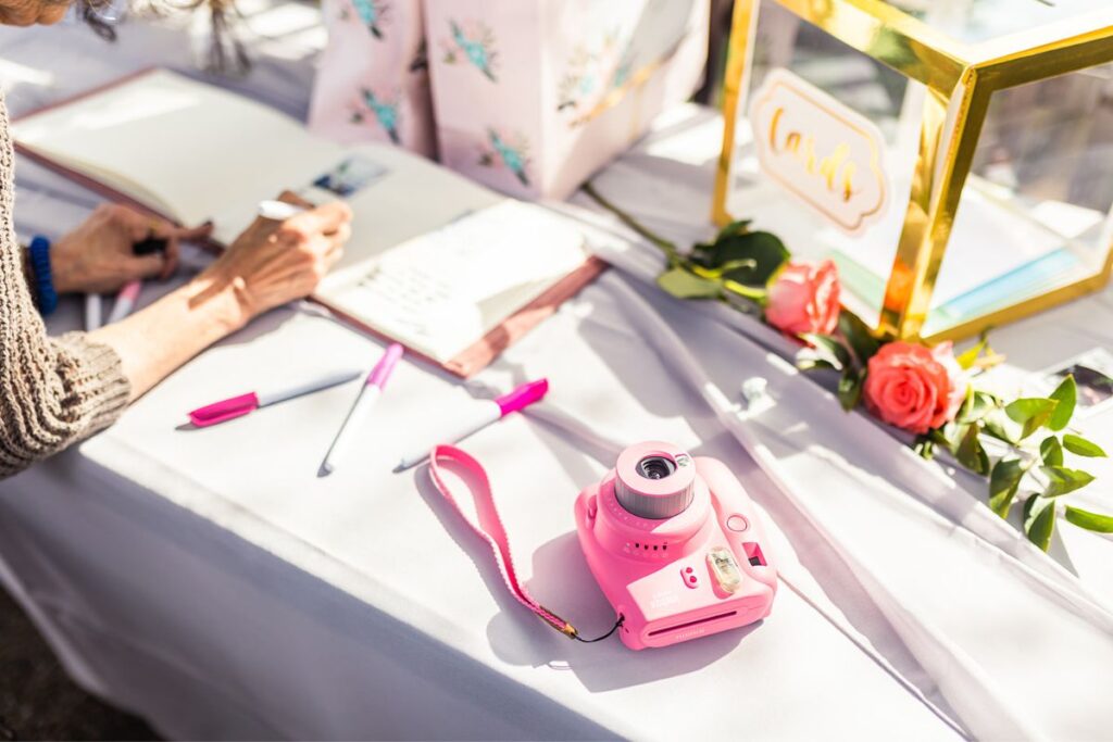 pink polaroid and guest writing into a guestbook as one of the nontraditional wedding ideas