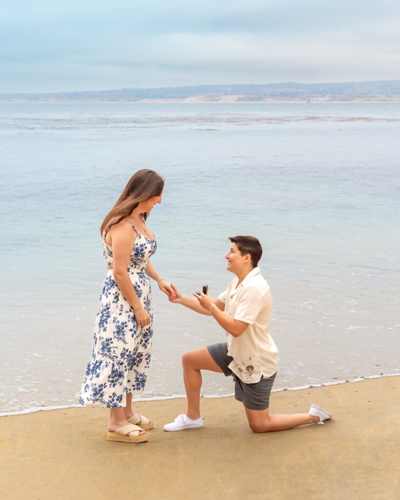 a queer couple getting engaged by the beach