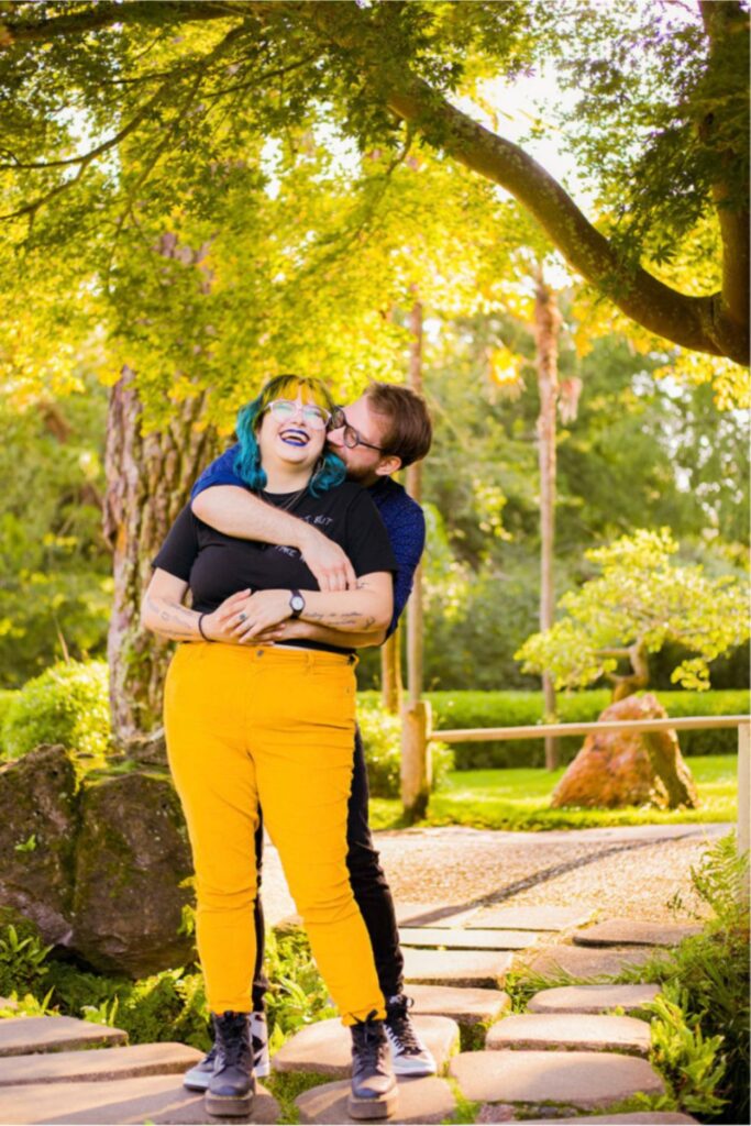 a lady yellow pants getting a loving kiss on a cheek in a park