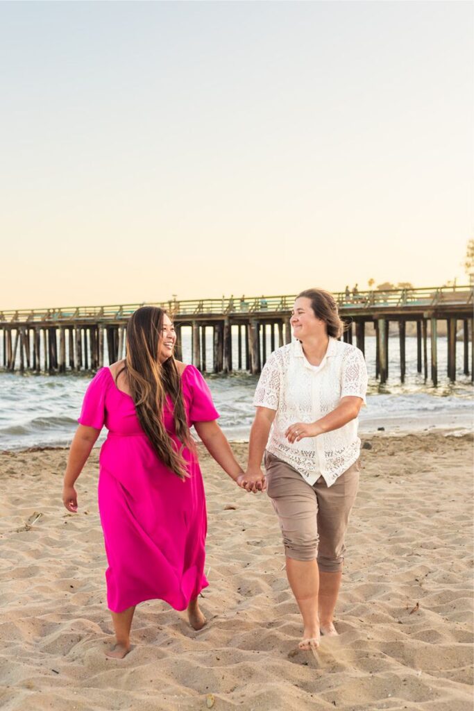 A couple walking down the beach and posing for their Santa Cruz engagement photos