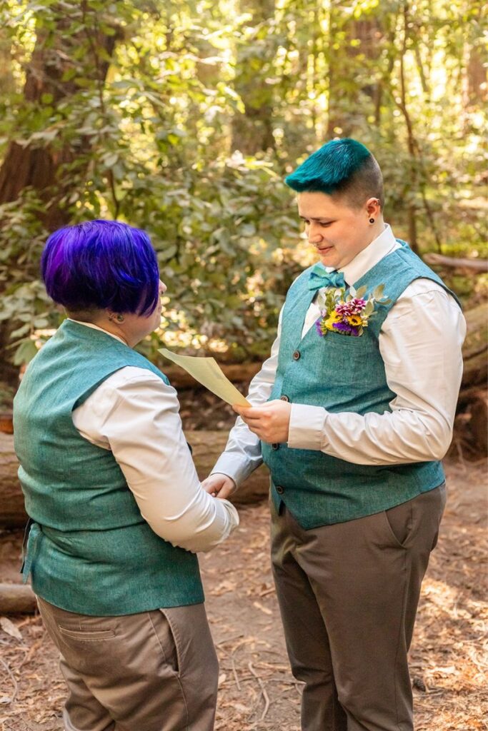 Nova and Arden reading their vows for their neurodivergent wedding in a forest