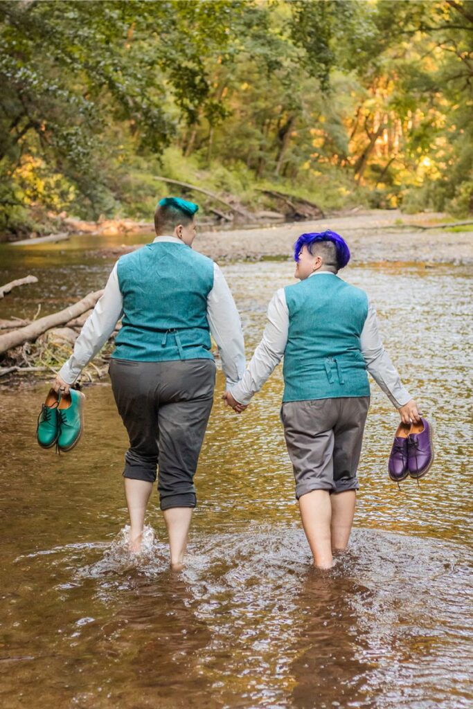 Nova and Arden walking barefoot hand in hand in a creek