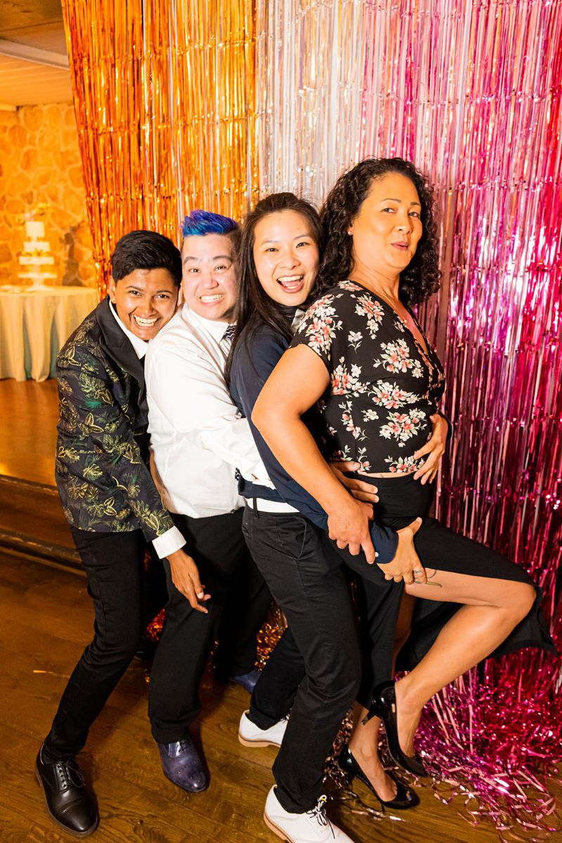 A group of four people at a wedding reception they are all hugging each other 