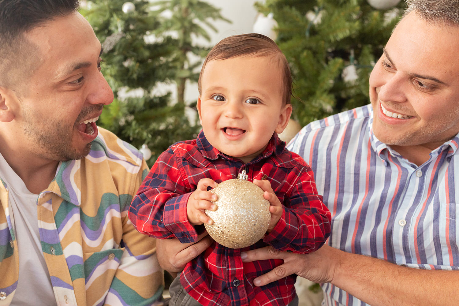 Two parents hold their child happily during a family holiday mini-session.