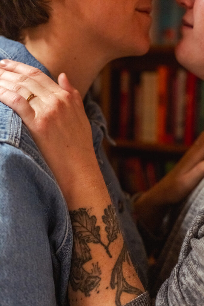 Close up of a person's hand on their partner's shoulder showing off an engagement ring 