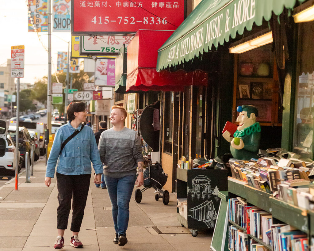 A couple holding hands and walking on a city sidewalk 