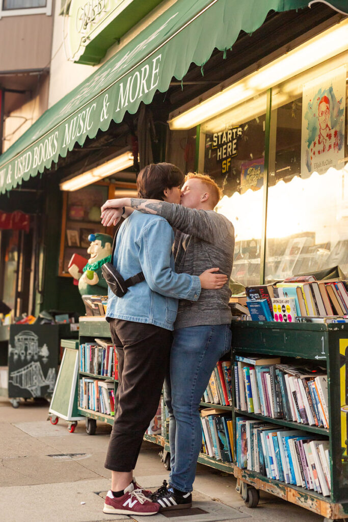 A couple kissing while standing outside of a bookstore 