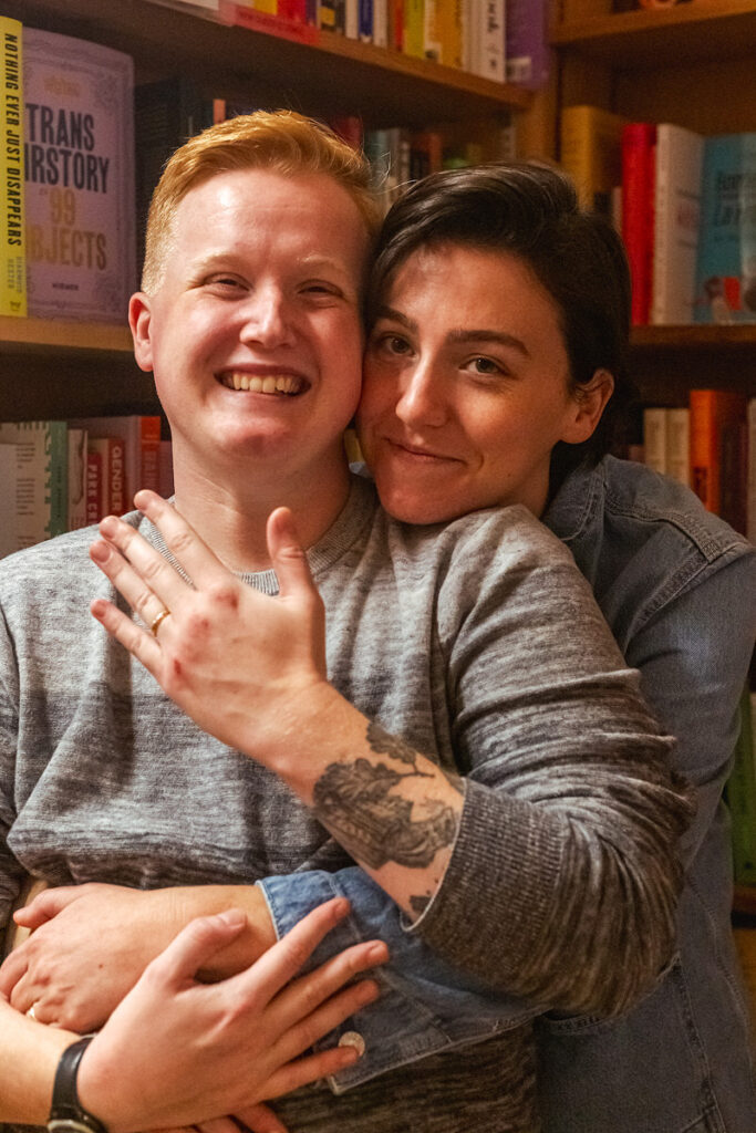 A person hugging their partner from behind as they show off an engagement ring 
