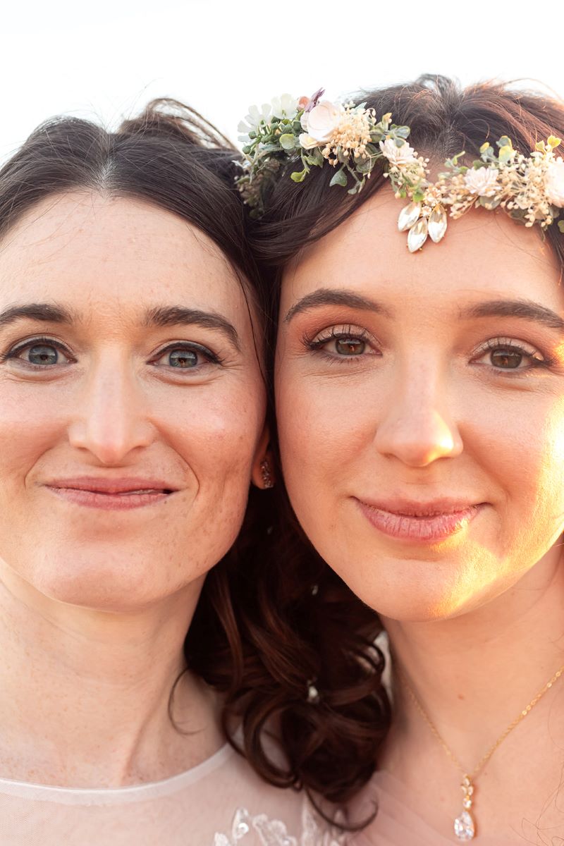 A couple smiling and one is wearing a flower crown