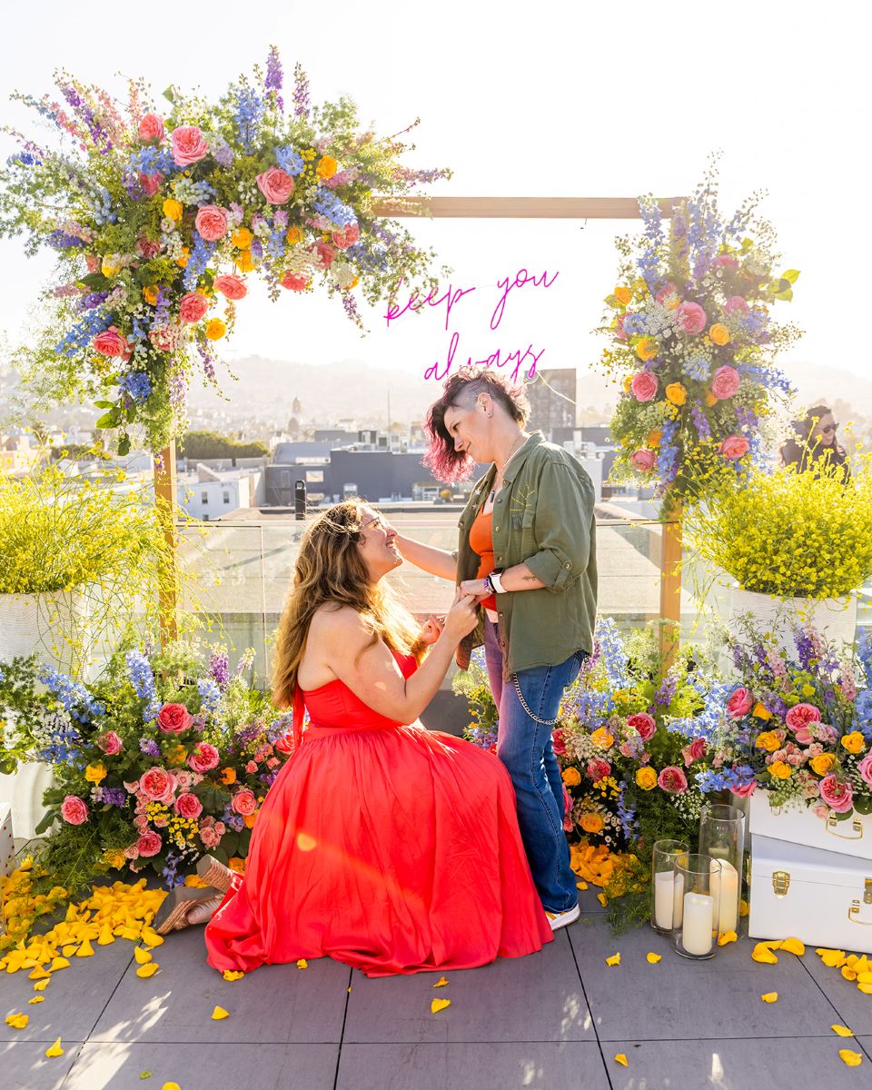an lgbtq proposal on the rooftop of biteunite in san francisco in front of an opulent and colorful floral arch