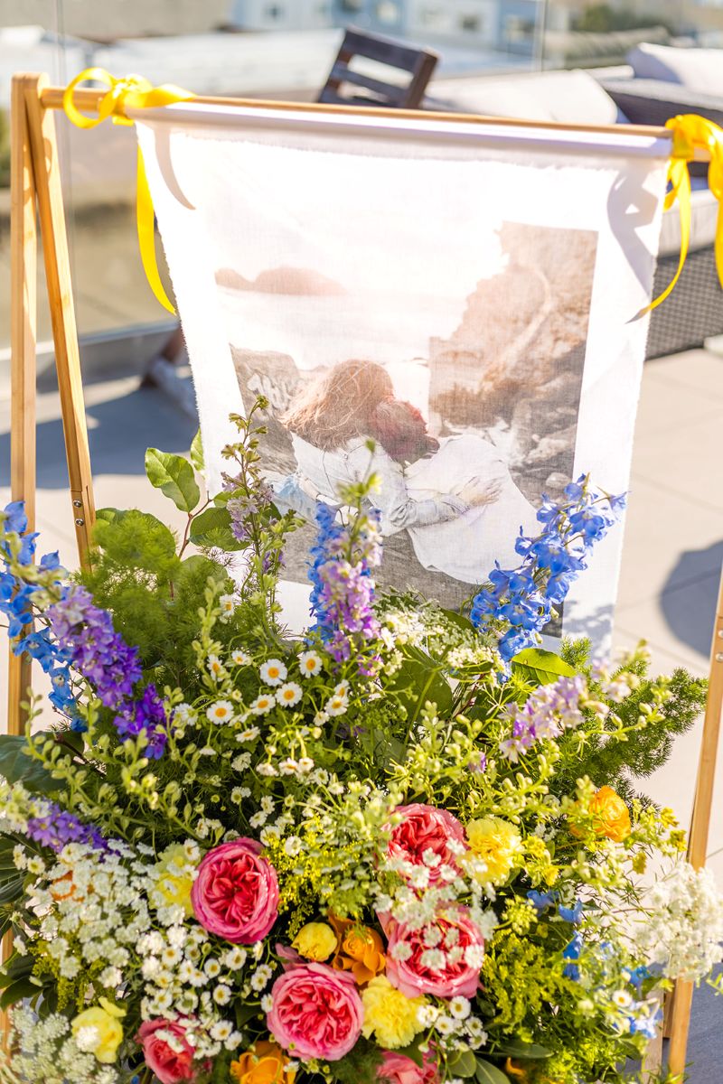 a wooden arch holding up a photo of a couple in front of it is a colorful and vibrant floral arrangment