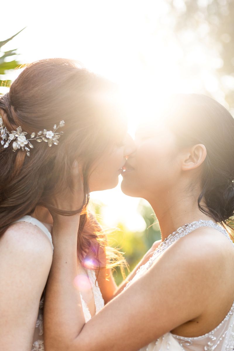 two women leaning in to kiss each other at sunset