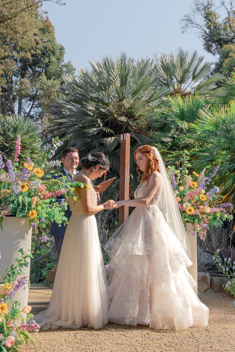 two women at their wedding ceremony at ruth bancroft garden one woman is placing a ring on the other woman's hand