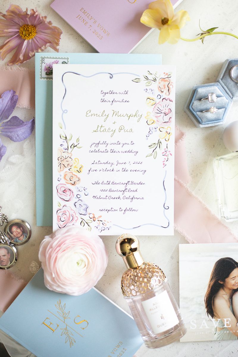 a flat lay with wedding invitations. perfume, a ring box and flowers