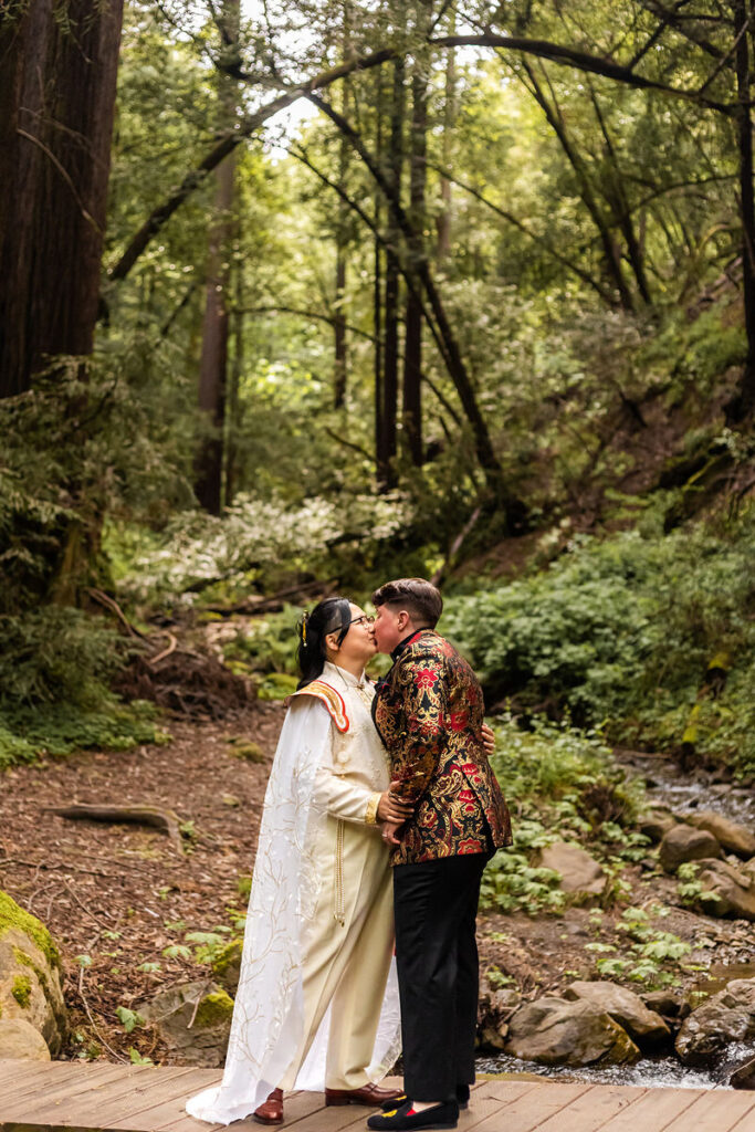 A wedding couple kissing while standing in the woods