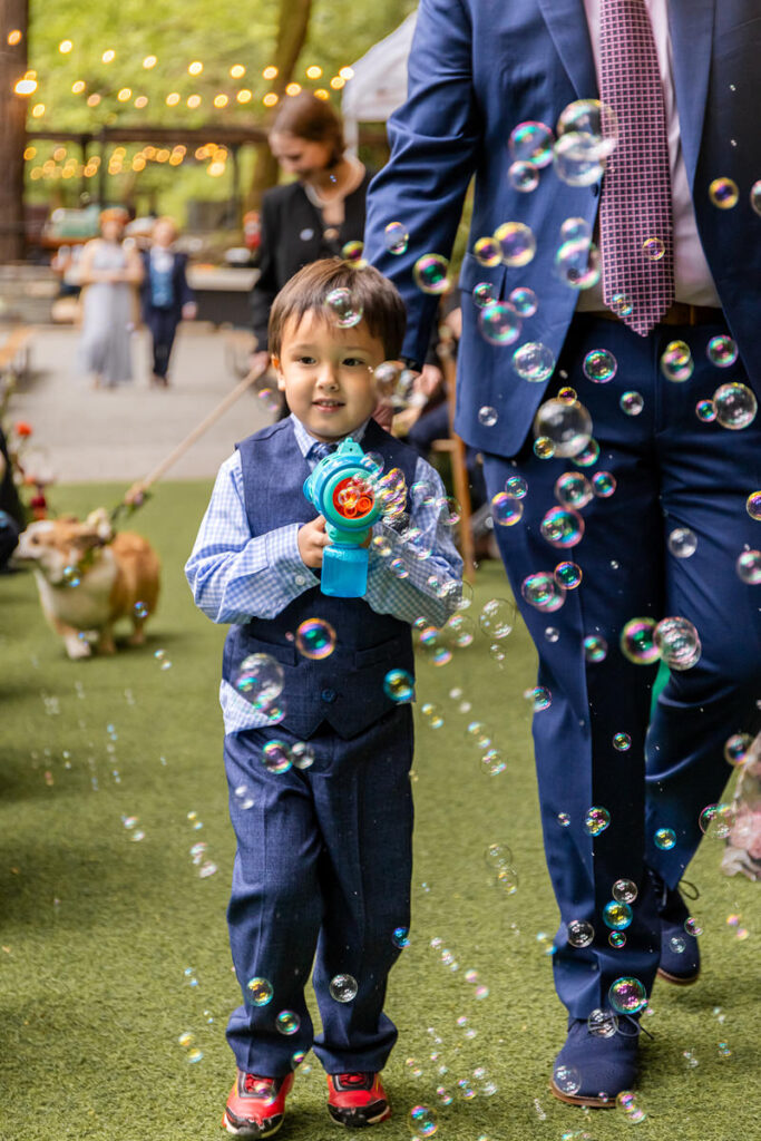 A small child walking down the aisle at a wedding with a bubble machine