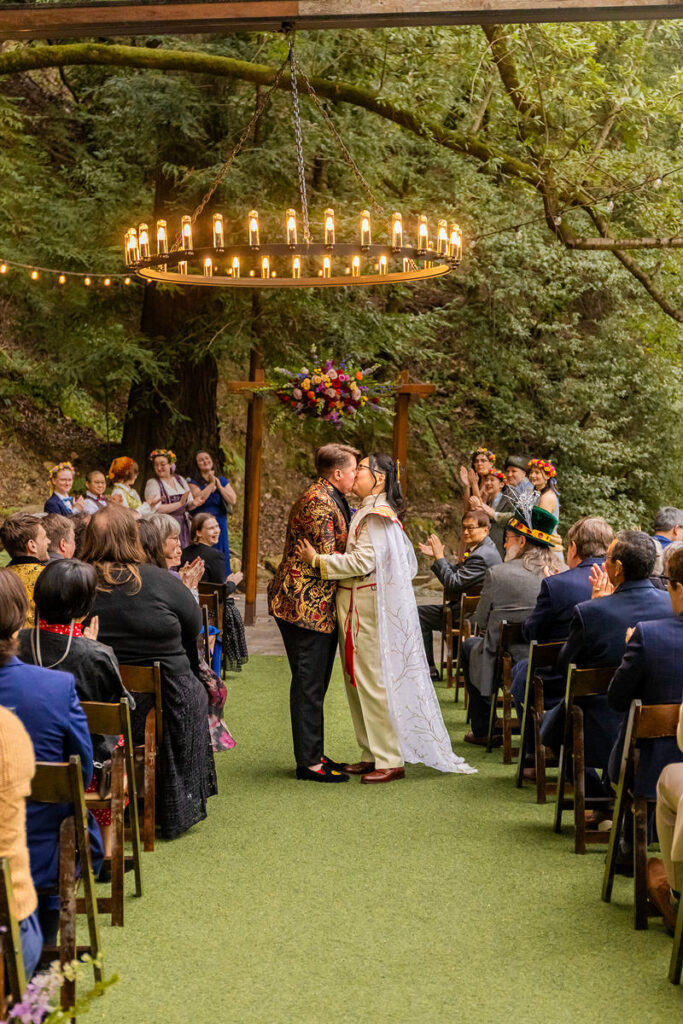 A newlywed couple kissing in the middle of the aisle during their wedding