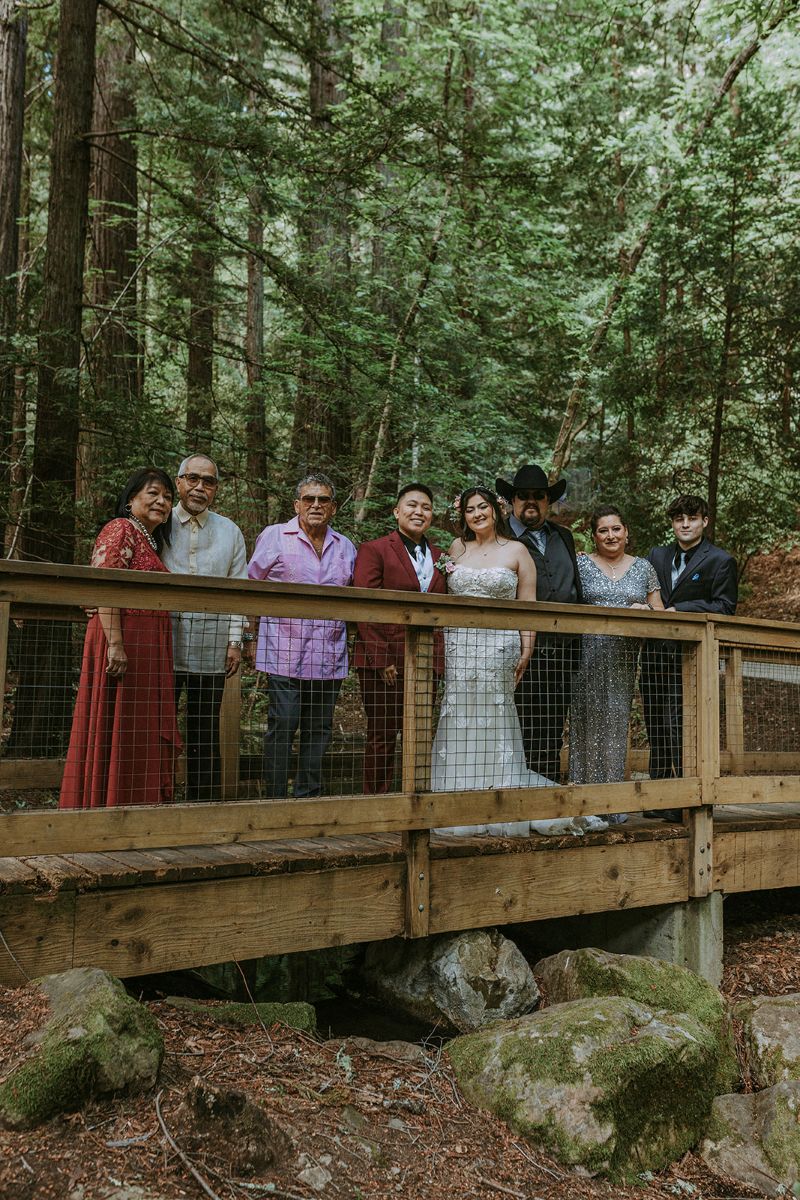 a queer couple posing with their family in sanborn county park on the bridge int he park