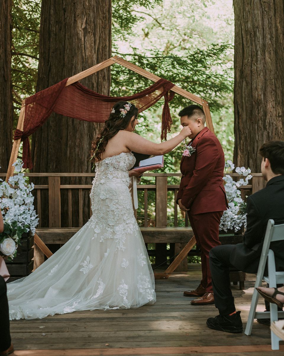 a couple having their wedding ceremony in peterson grove in saratoga california one partner is wiping tears from their partner's eyes