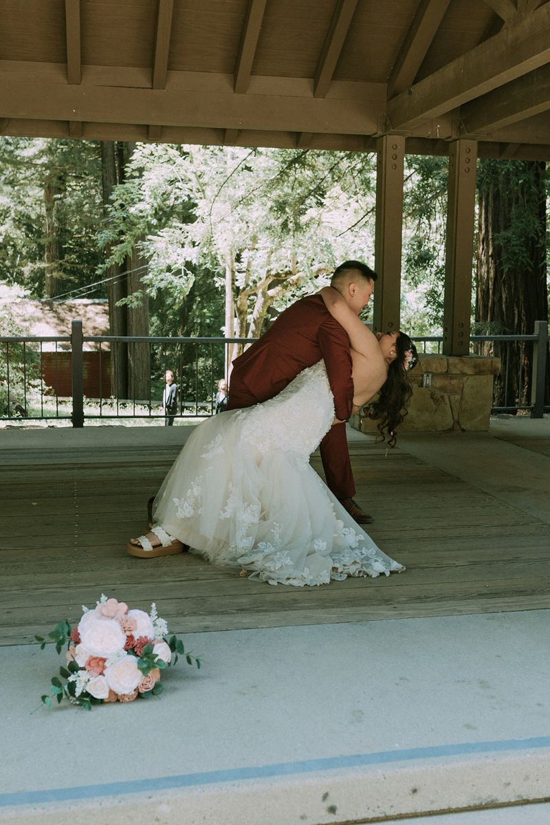 a queer couple having their first dance in sanborn county park one person is dipping the other backwards and they are both smiling at each other