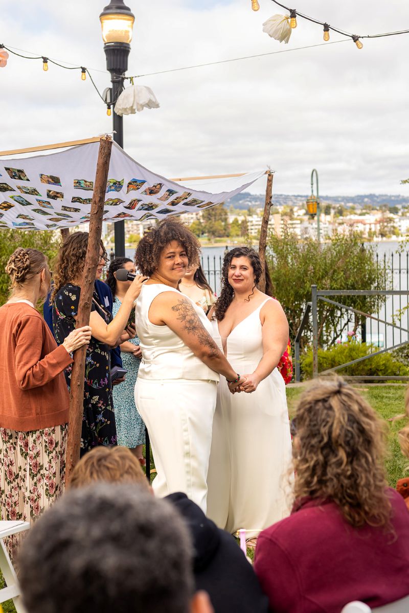 a couple at their wedding ceremony at camron stanford house they are having their celebration in the yard of the museum next to the lake 