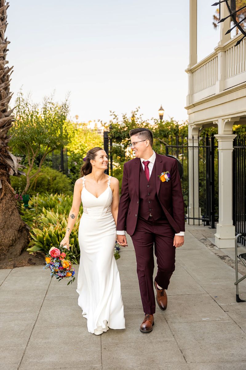 a couple walking hand in hand  at camron stanford house on the day of their wedding 
