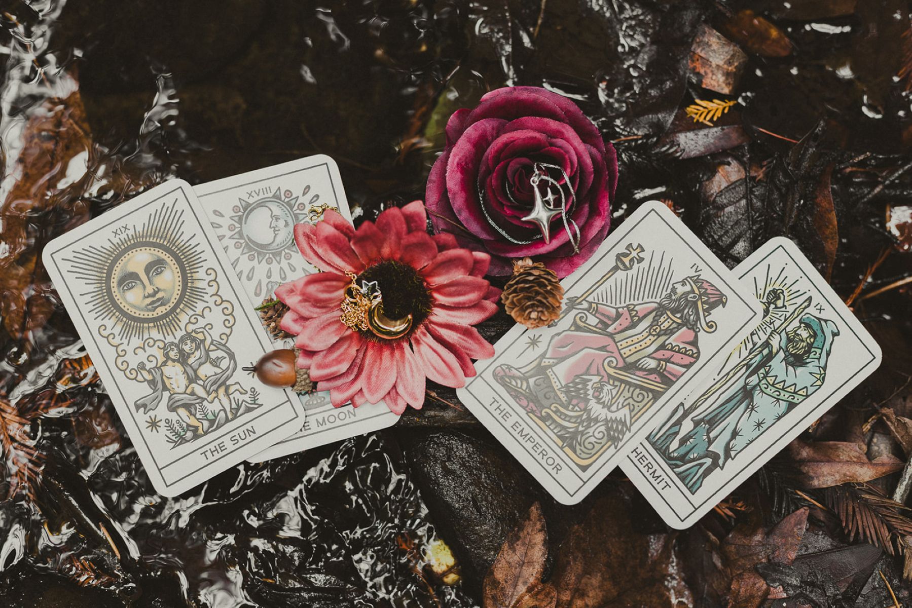 tarot cards, rings, and flowers on the ground 