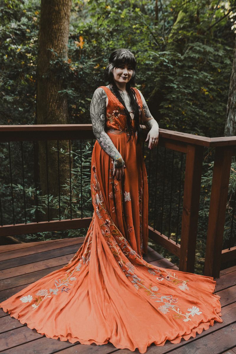 a person standing in vibrant orange wedding dress on a porch behind them is the henry cowell state park forest 
