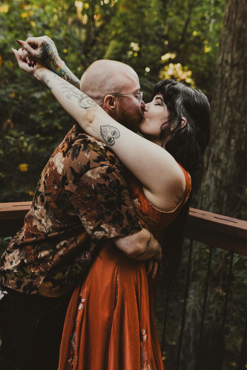 a couple kissing on a porch deck on the day of their wedding 