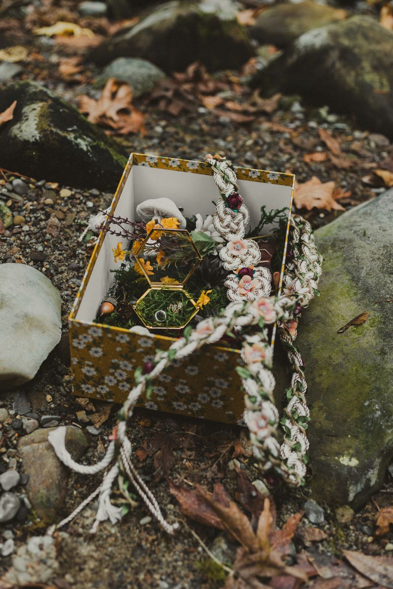 a box sitting on top of a rock with rings, jewelery, moss, and a cord for a wiccan ceremony 