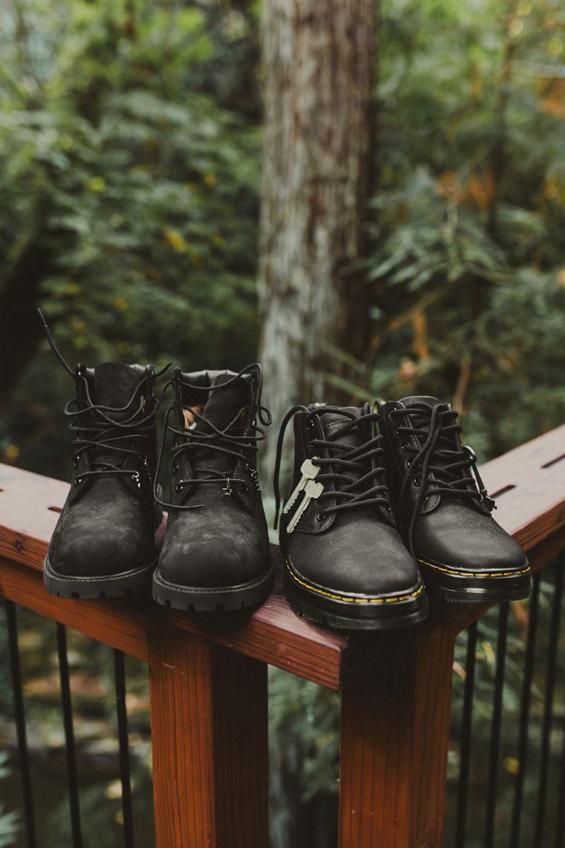 two pairs of black boots sitting on a porch deck railing 