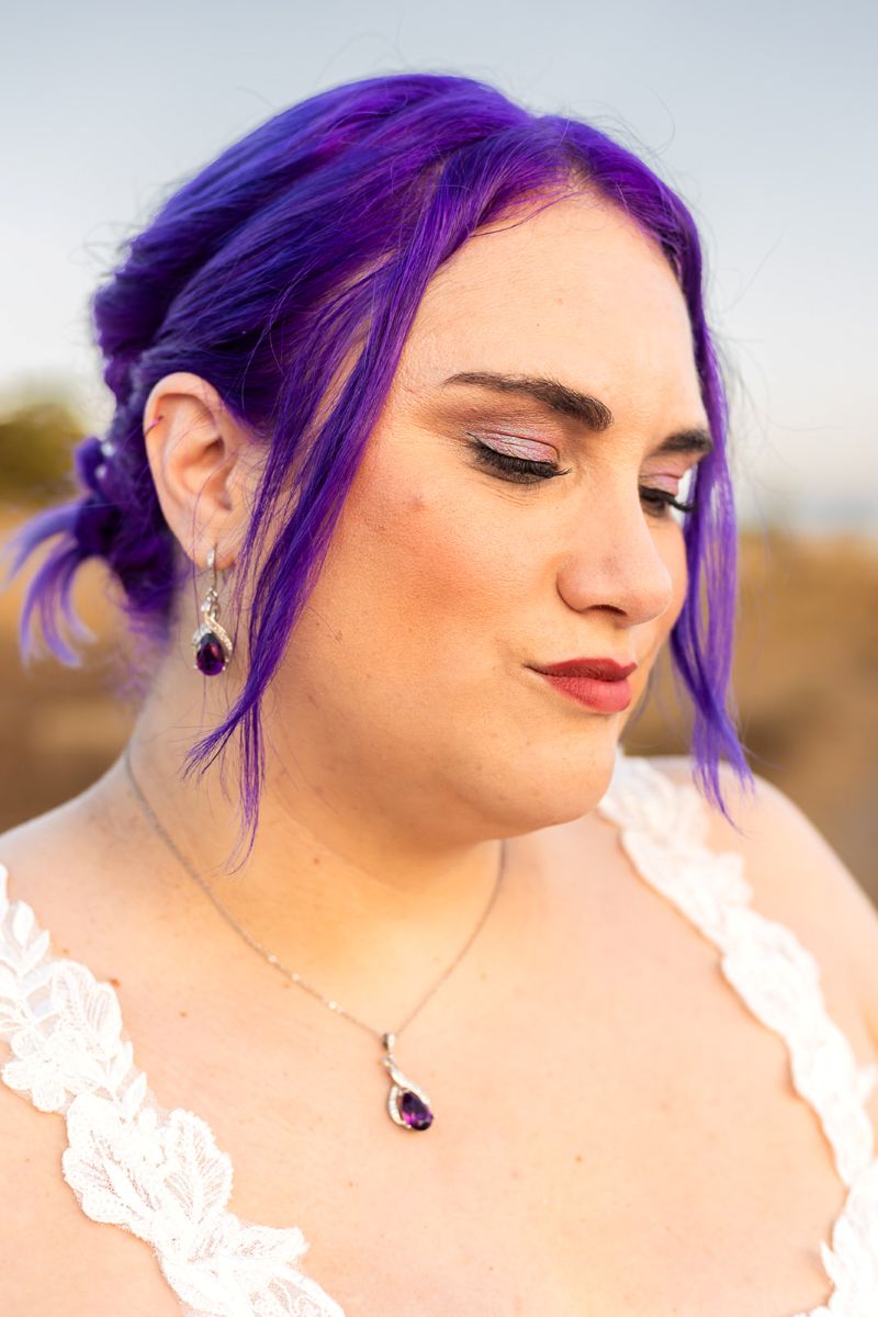 a person with purple hair that matches their earrings and necklace and eye shadow 