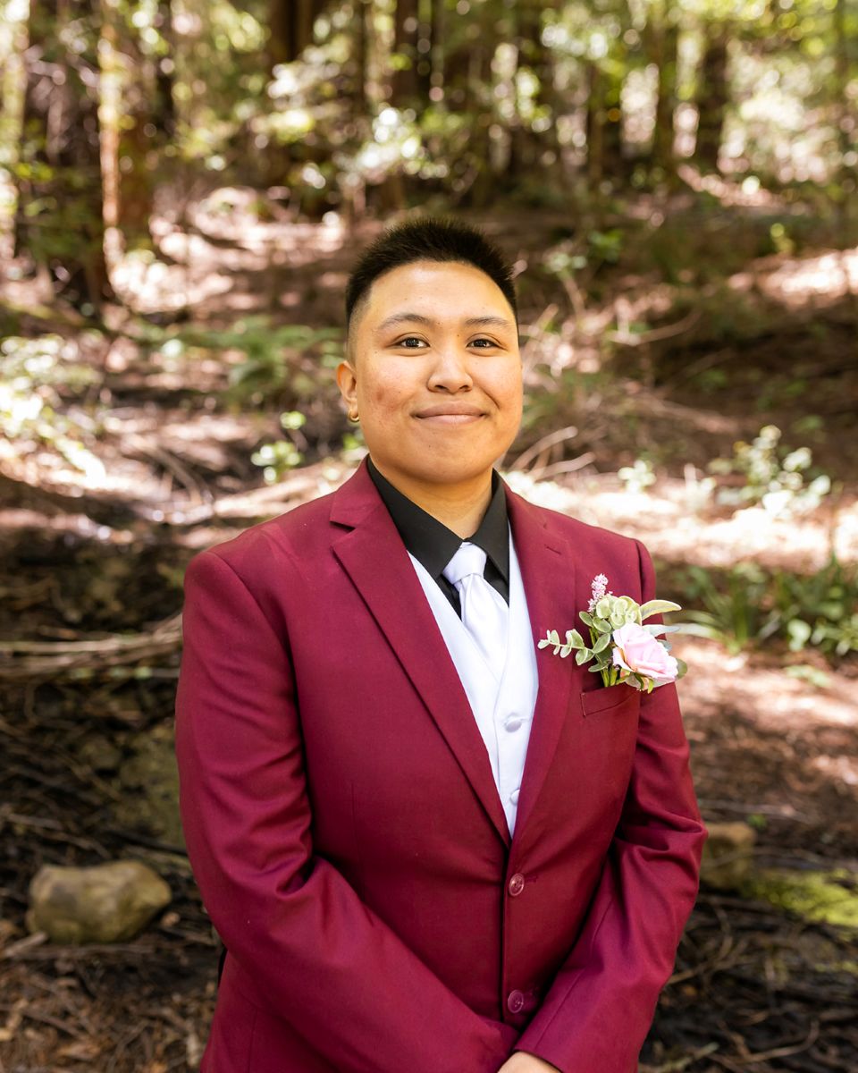 a person wearing a burgundy suit and softly smiling 