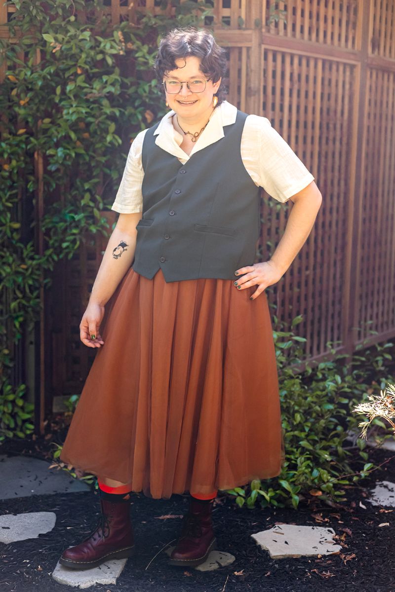 a person wearing a red skirt and black boots with their hand on their hip 