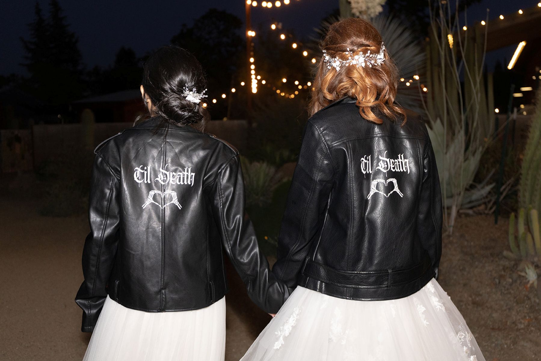 a couple wearing white wedding dresses and black leather jackets that say til death at their wedding reception