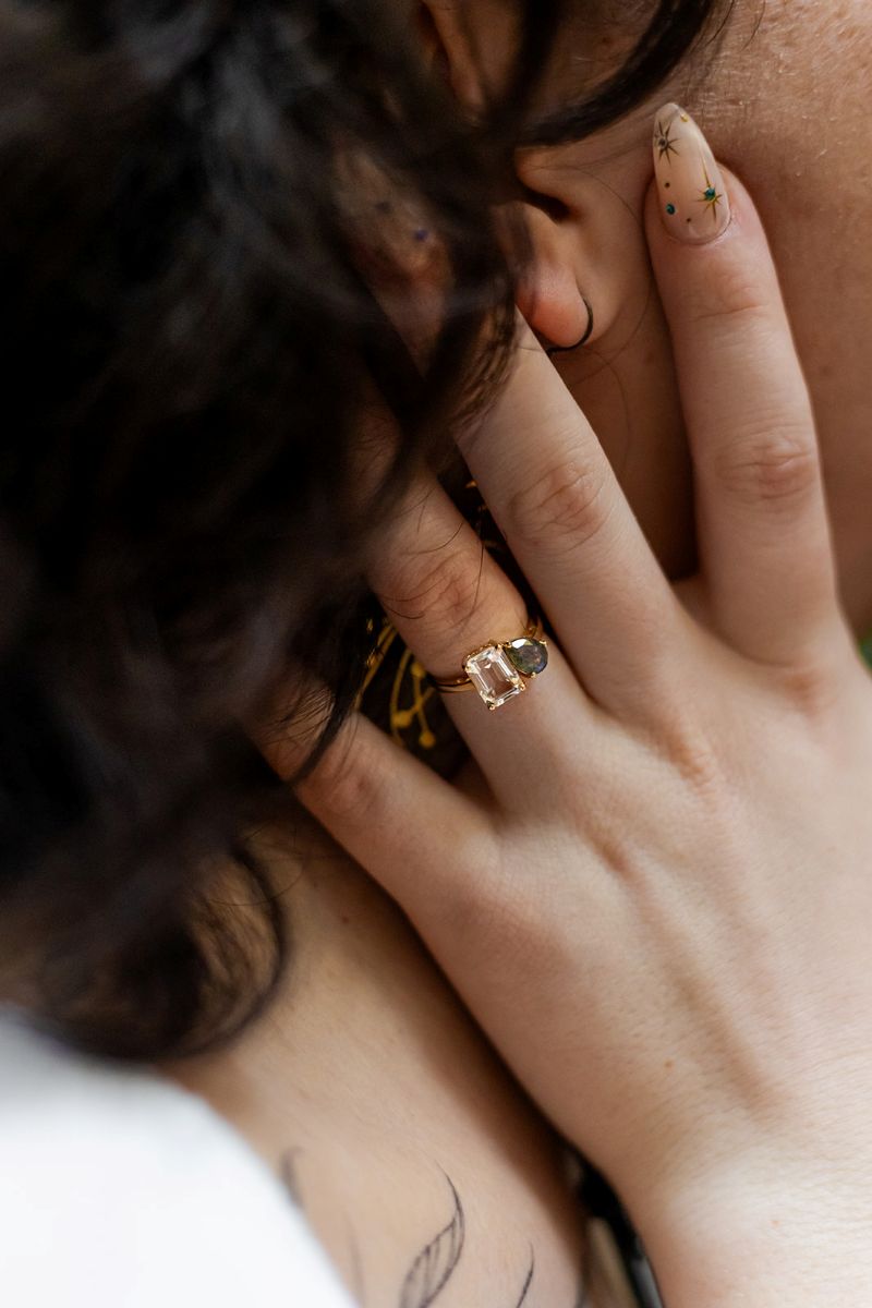 a woman showing off her engagement ring and touching her partner's cheek 