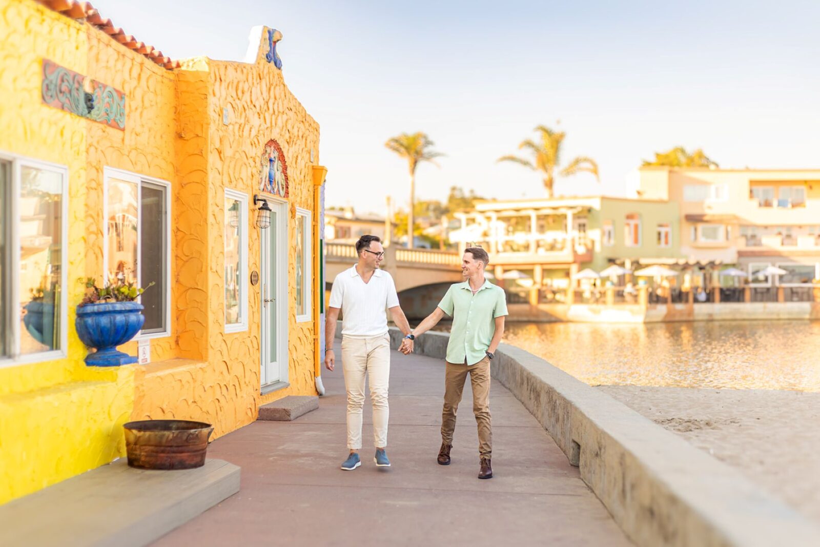 a couple walking hand in hand smiling at each other at capitola beach at sunset 