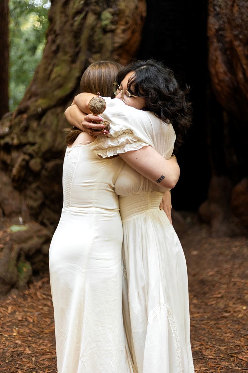 a couple embracing after one woman proposed to her partner in henry cowell state park 
