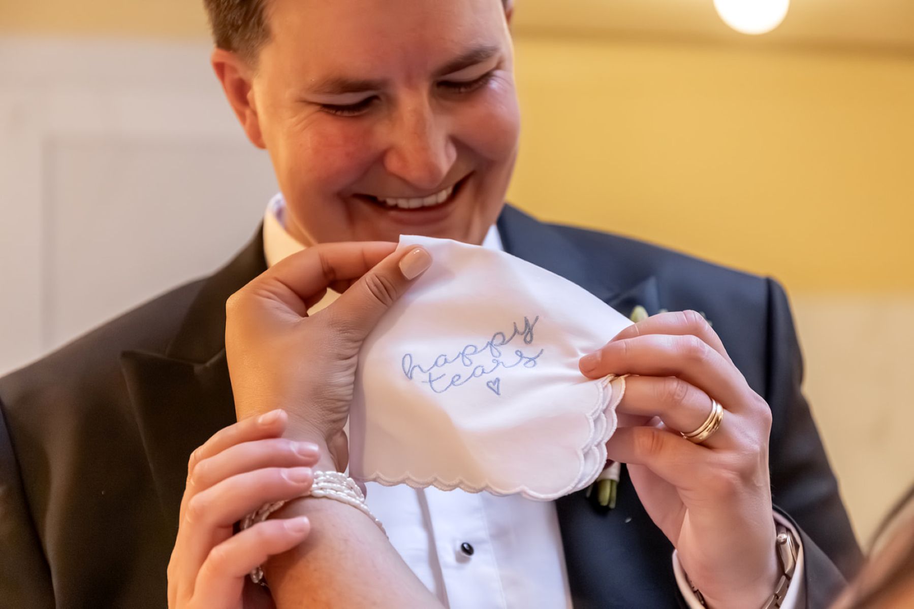 a couple holding up a personalized hanky on the day of their wedding that says happy tears