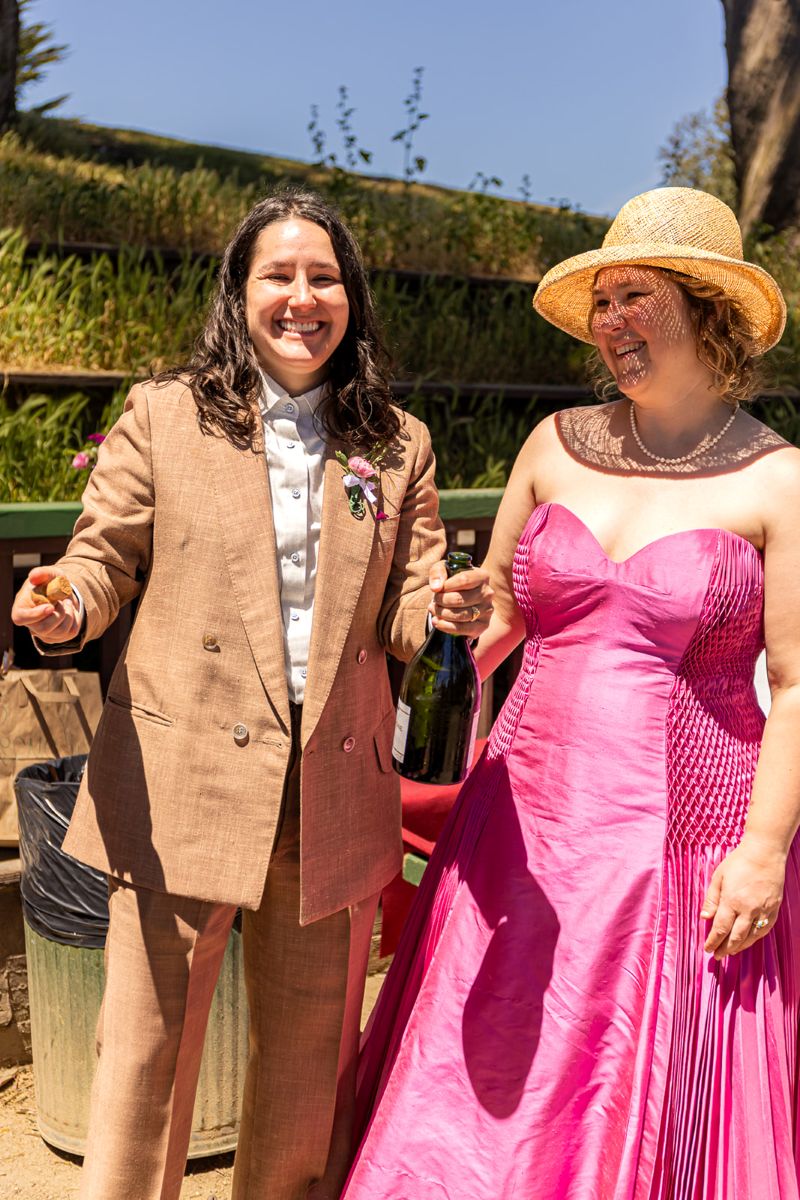 a couple popping a bottle of champagne for their outdoor bbq wedding reception