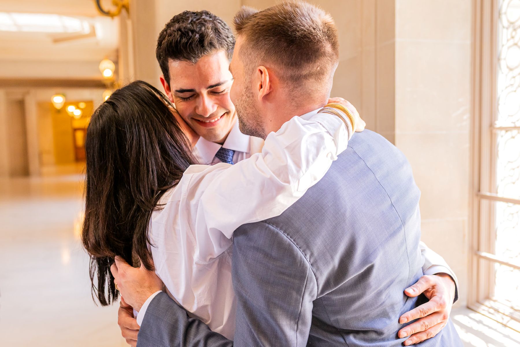 a woman embracing a couple after their wedding ceremony in san francisco city hall