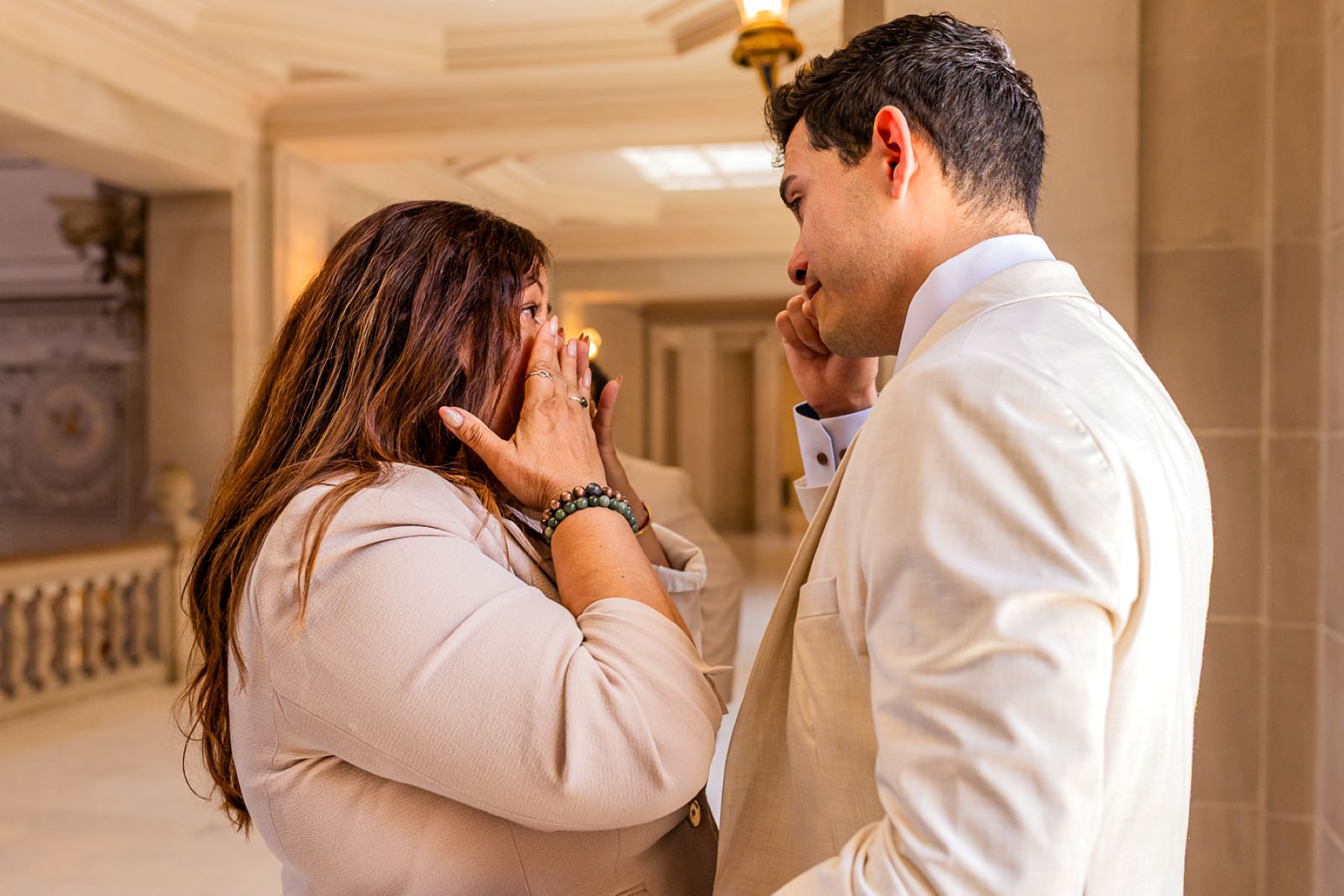 a man wiping tears away and talking to his mom who is also wiping tears from her face after his wedding at san francisco city hall