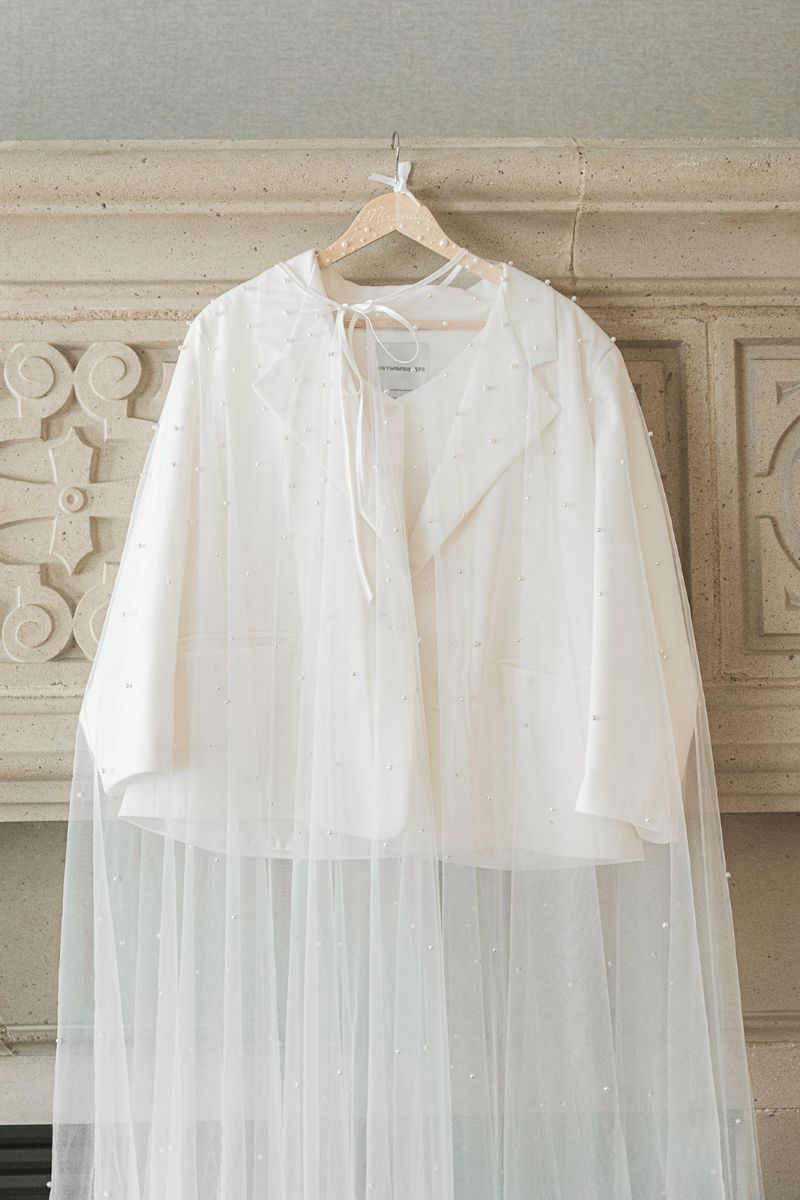 a white top with a pearl cape over int hanging on a hanger