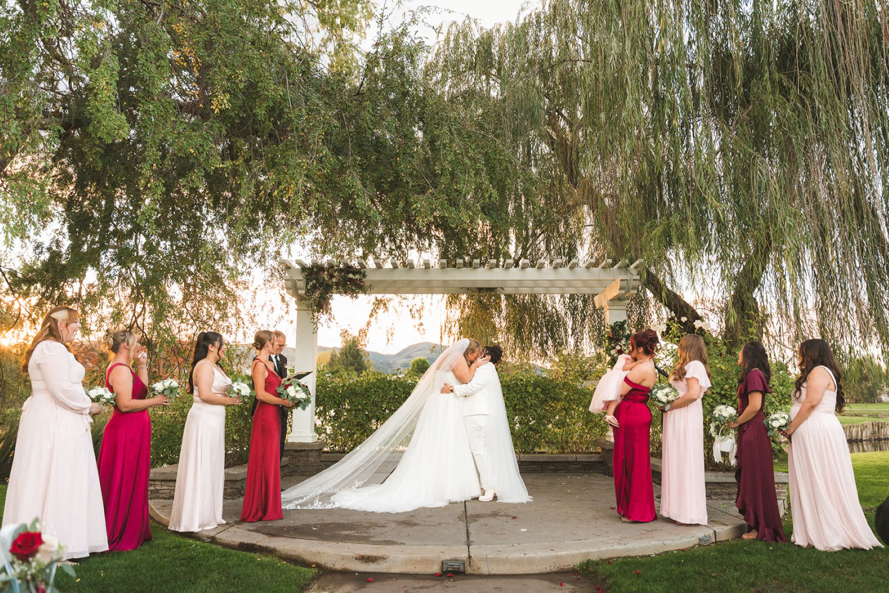 a lesbian couple having their wedding ceremony at san ramon waters they are kissing and next to them on both sides is their wedding party