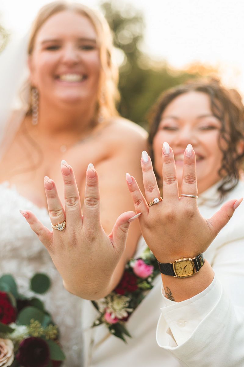 two brides showing off their wedding rings